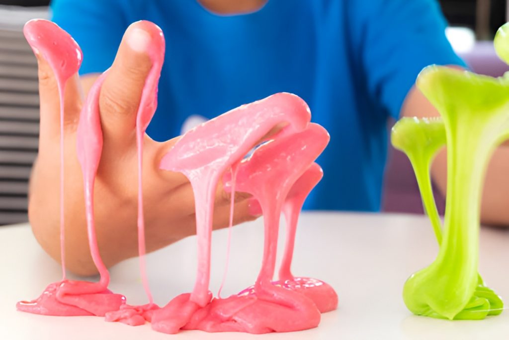 boy's hands covered in pink and green slime