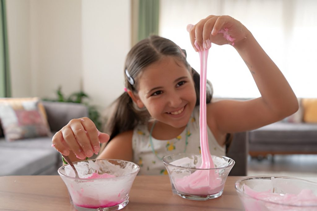 smiling girl stretching butter slime from a bowl