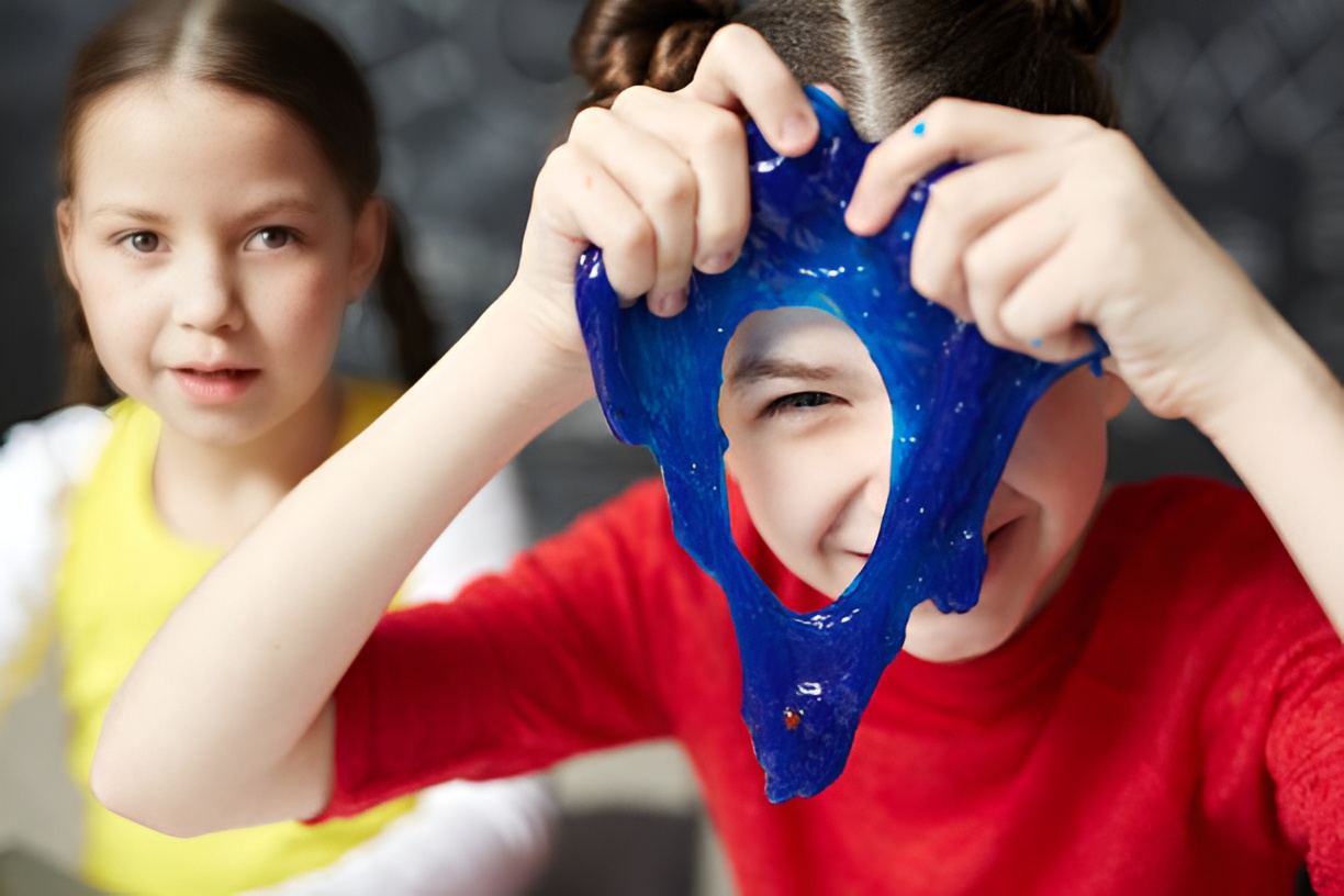 smiling girl looking through a hole in blue slime